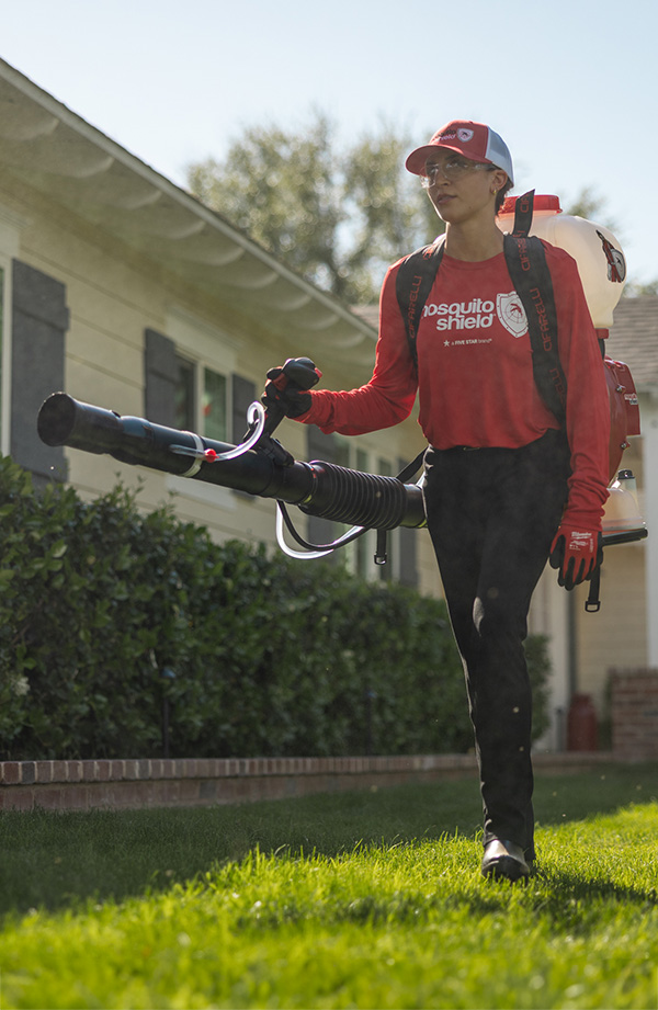 Vertical photo of female tech spraying hedge in the twin cities north